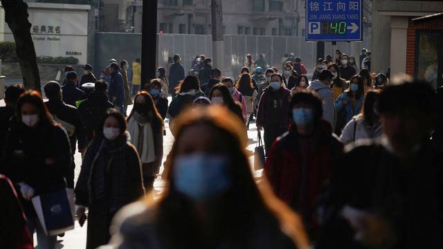 FILE PHOTO: People wearing protective masks walk on a street, following new cases of the coronavirus disease (COVID-19), in Shanghai