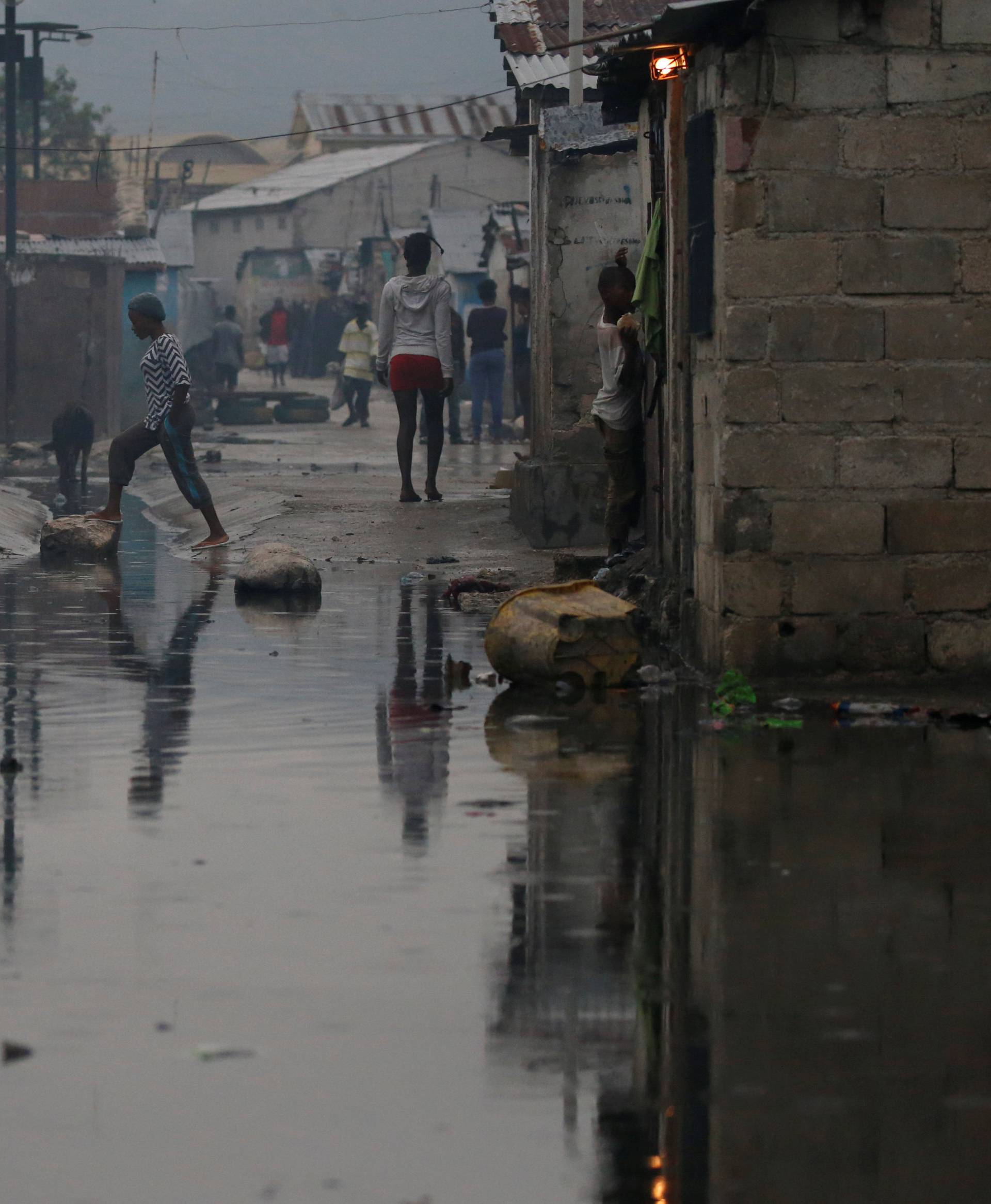 People walk on a flooded street after Hurricane Matthew passes Cite-Soleil in Port-au-Prince