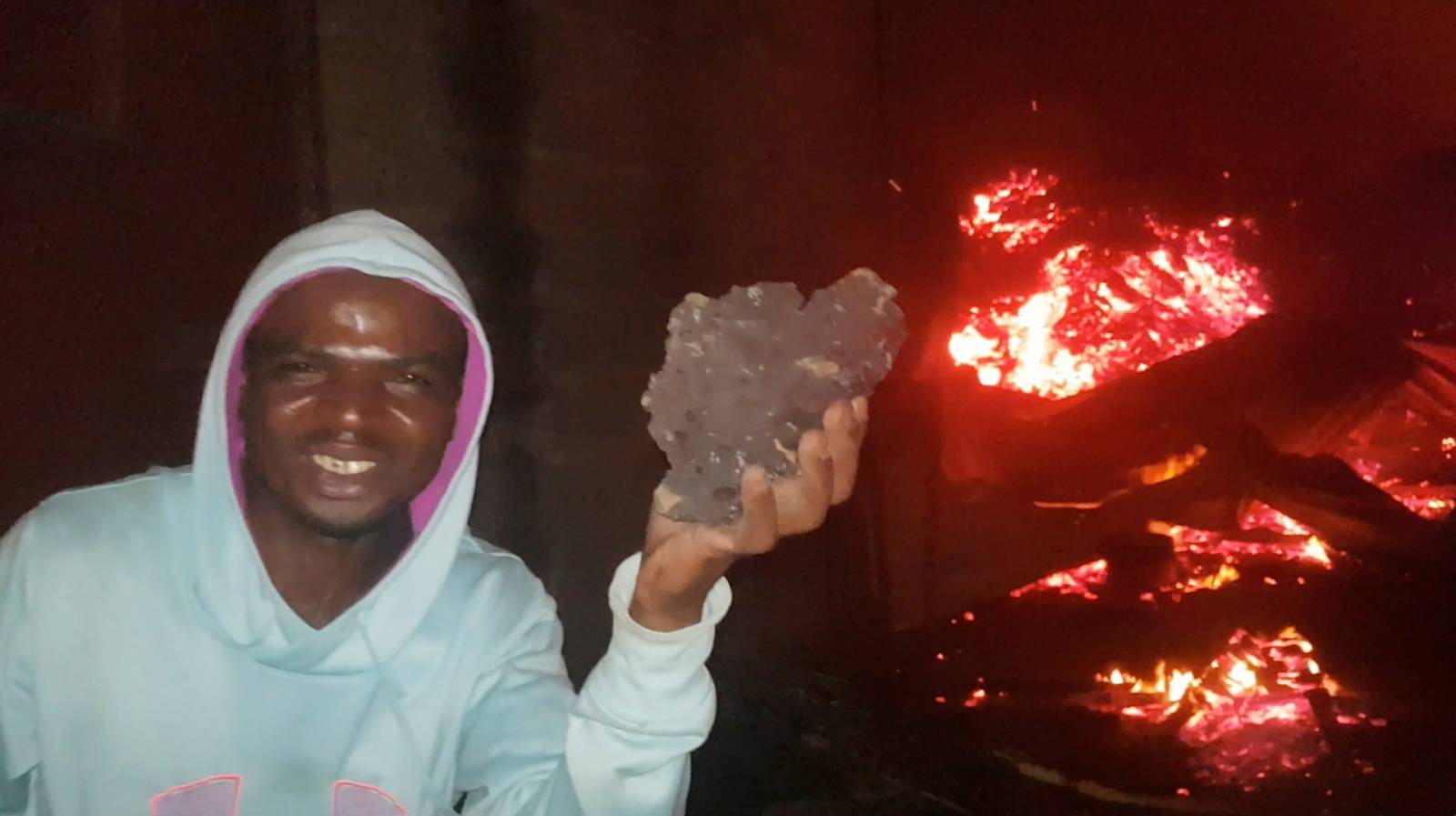 A person reacts near debris and flowing lava from the volcanic eruption of Mount Nyiragongo, in Goma