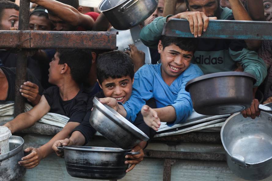 Palestinians wait to receive food from a charity kitchen, amid a hunger crisis, in Gaza City
