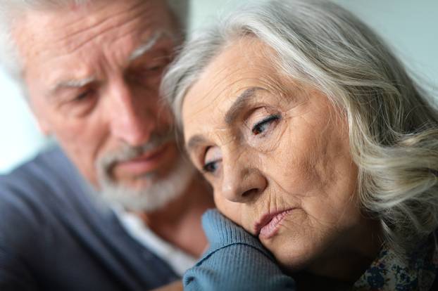 Portrait of cute sad senior couple posing at home