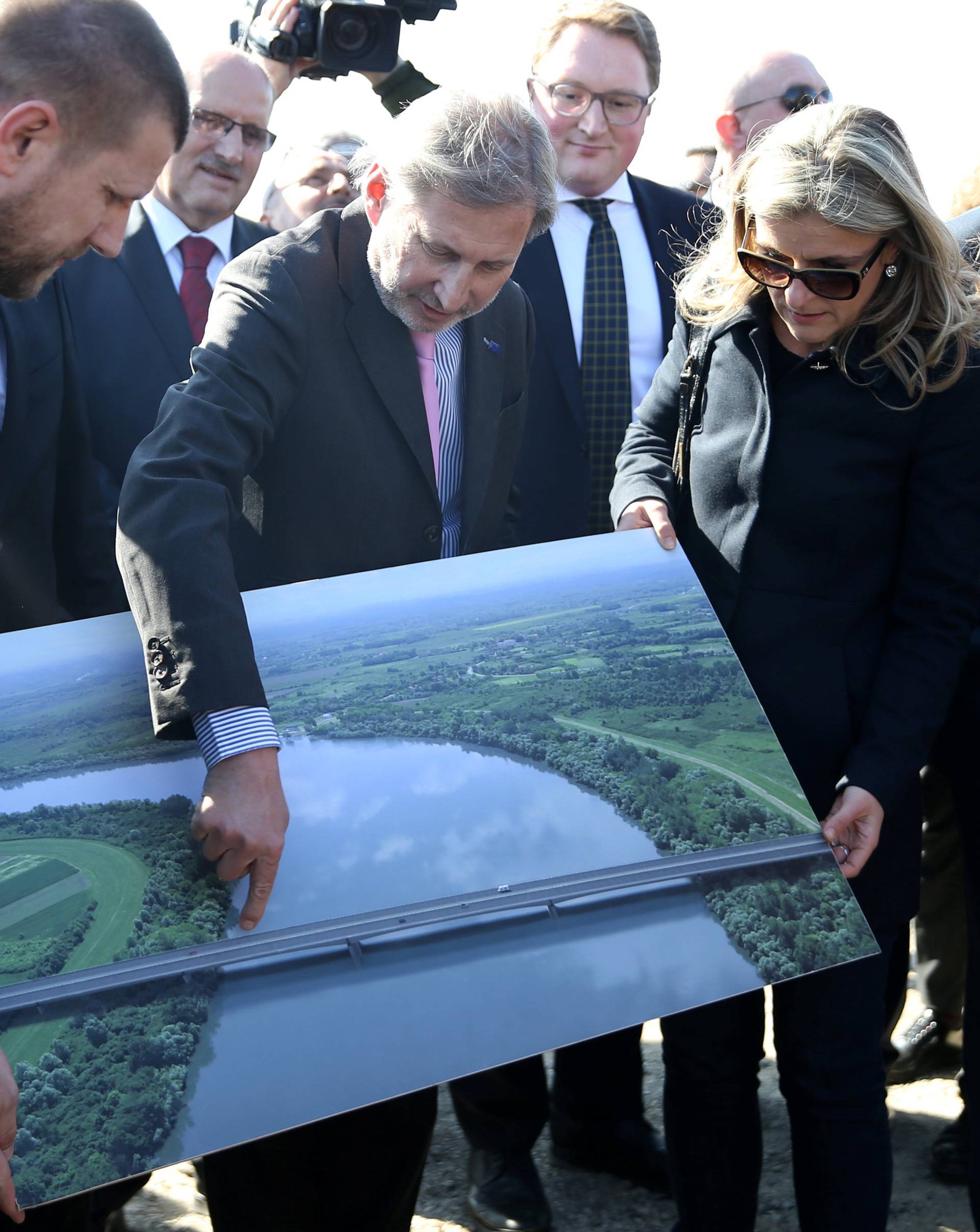EU Enlargement Commissioner Johannes Hahn points at a picture of the EU-funded cross-border bridge as he attends the opening ceremony of the bridge, in Donji Svilaj