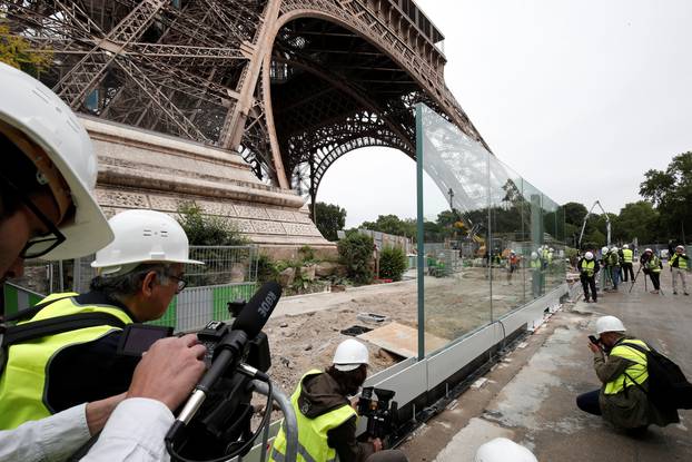 Members of the media make images of the new glass security fence which is under construction around the Eiffel Tower in Paris