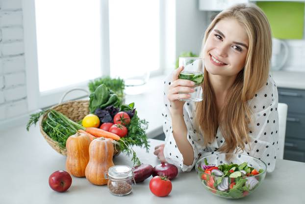 Young,Woman,Drinking,Water,Near,The,Table,With,Fruits,And