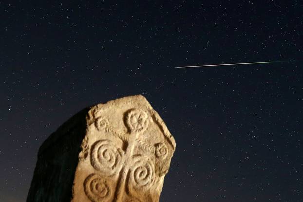A meteor streaks past stars in the night sky above medieval tombstones in Radmilje near Stolac, south of Sarajevo