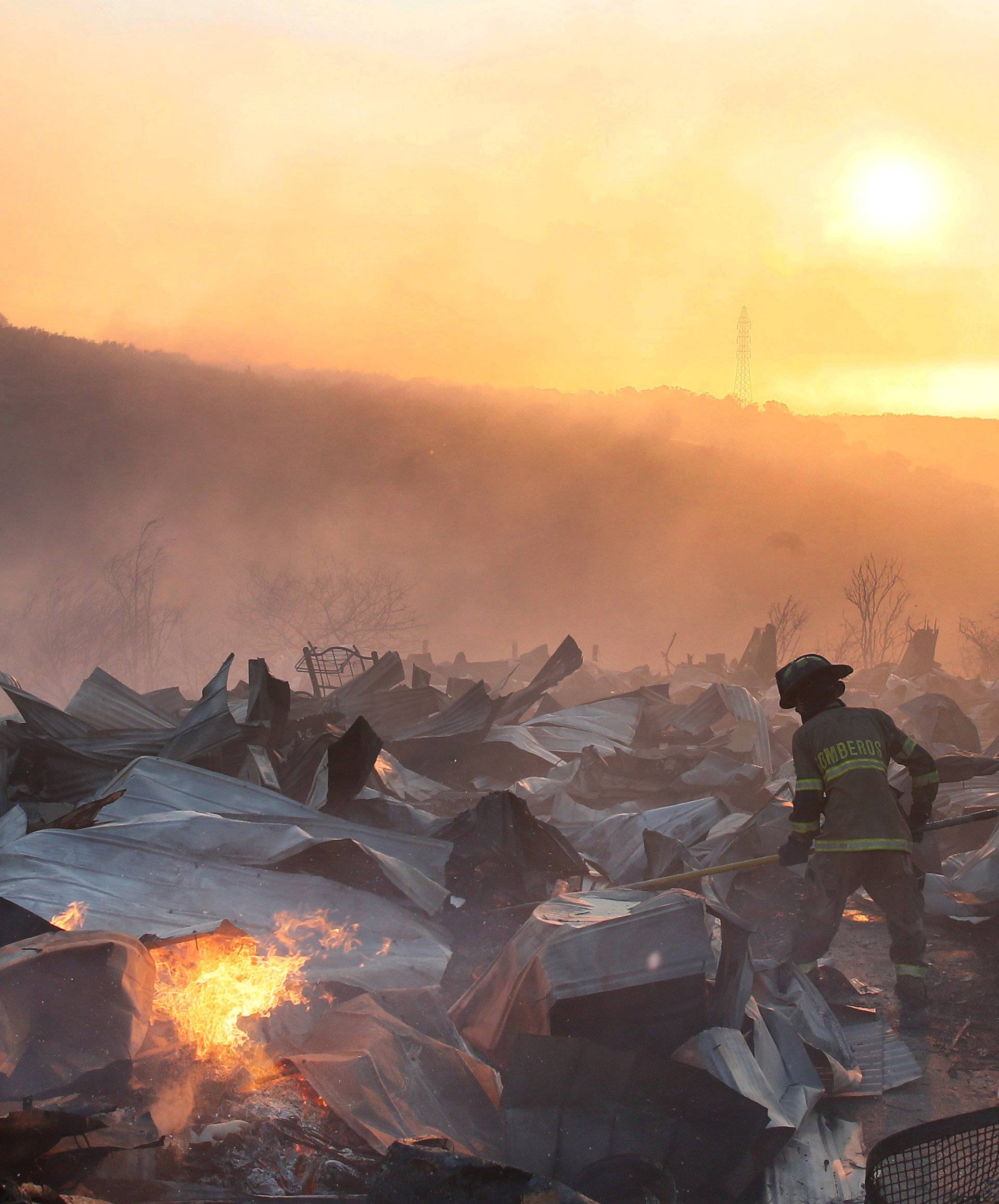 A firefighter removes the remains of a burned house on a hill, where more than 100 homes were burned due to forest fire but there have been no reports of death, local authorities said in Valparaiso, Chile