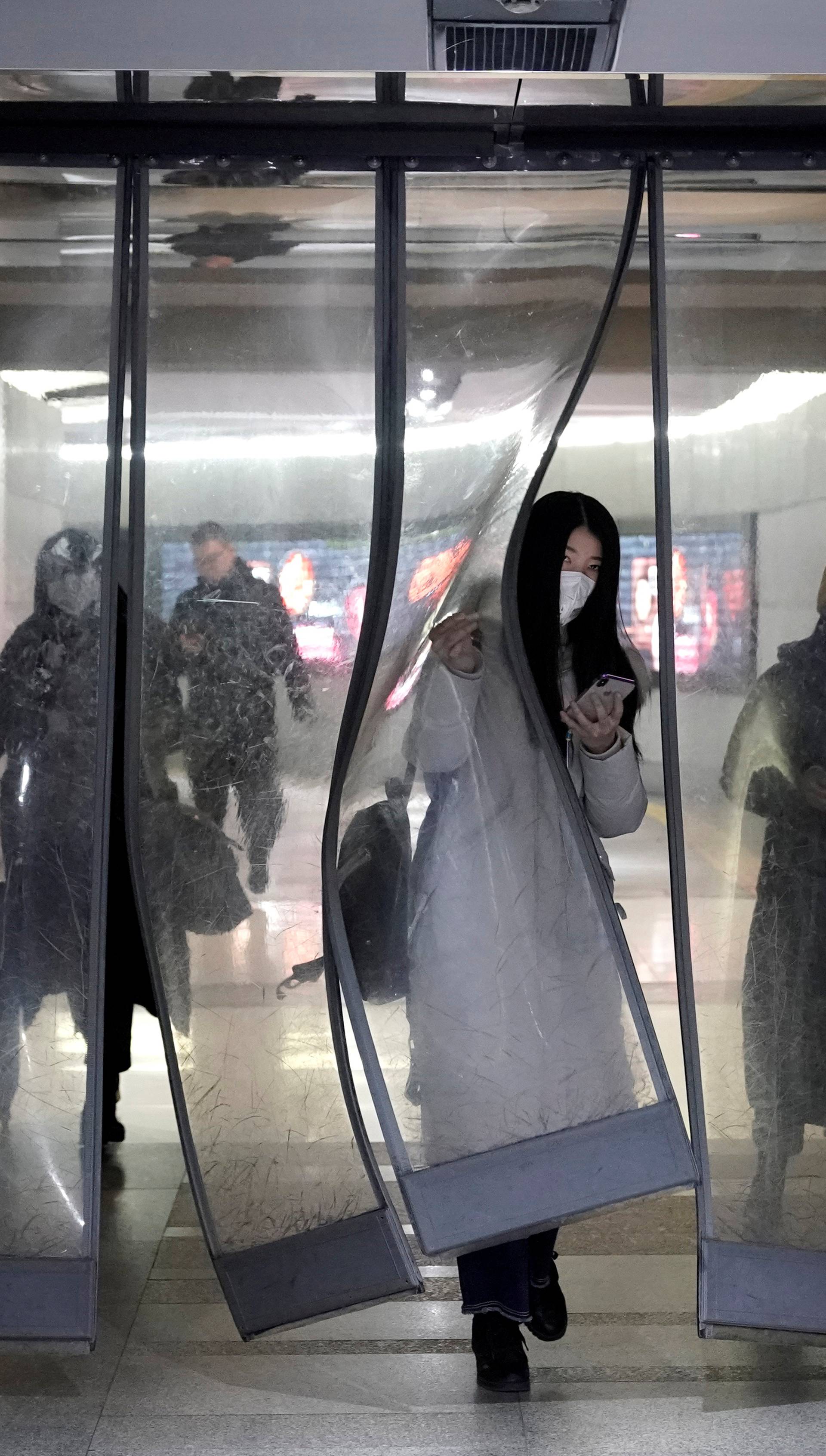 People wearing masks walk through an underground passage to the subway in Beijing