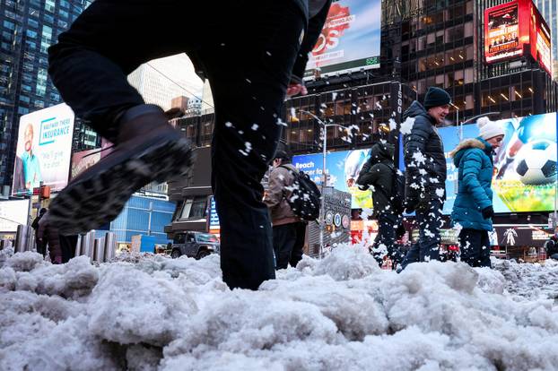 Morning commuters walk through snow in Times Square in New York