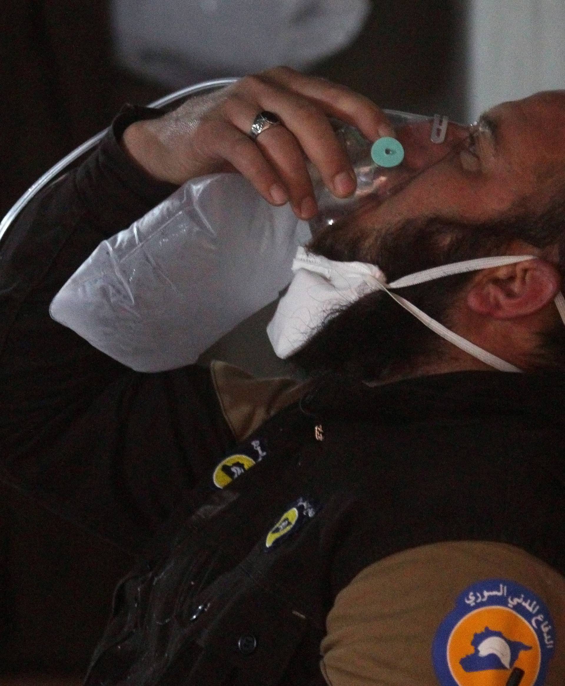 A civil defense member breathes through an oxygen mask, after what rescue workers described as a suspected gas attack in the town of Khan Sheikhoun in rebel-held Idlib