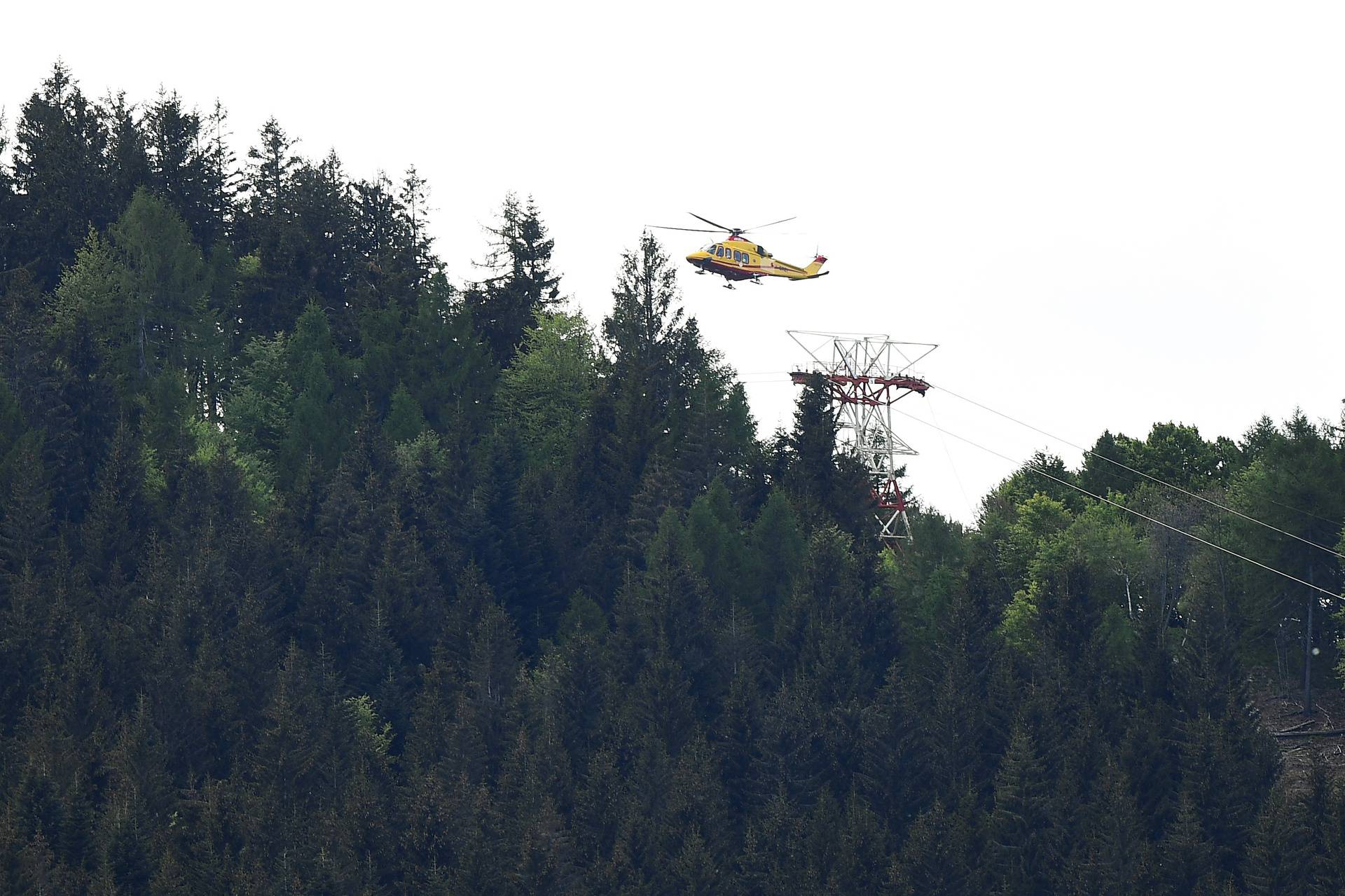 A helicopter flies over the site where a cable car connecting Maggiore lake with a mountain close by collapsed, in Stresa