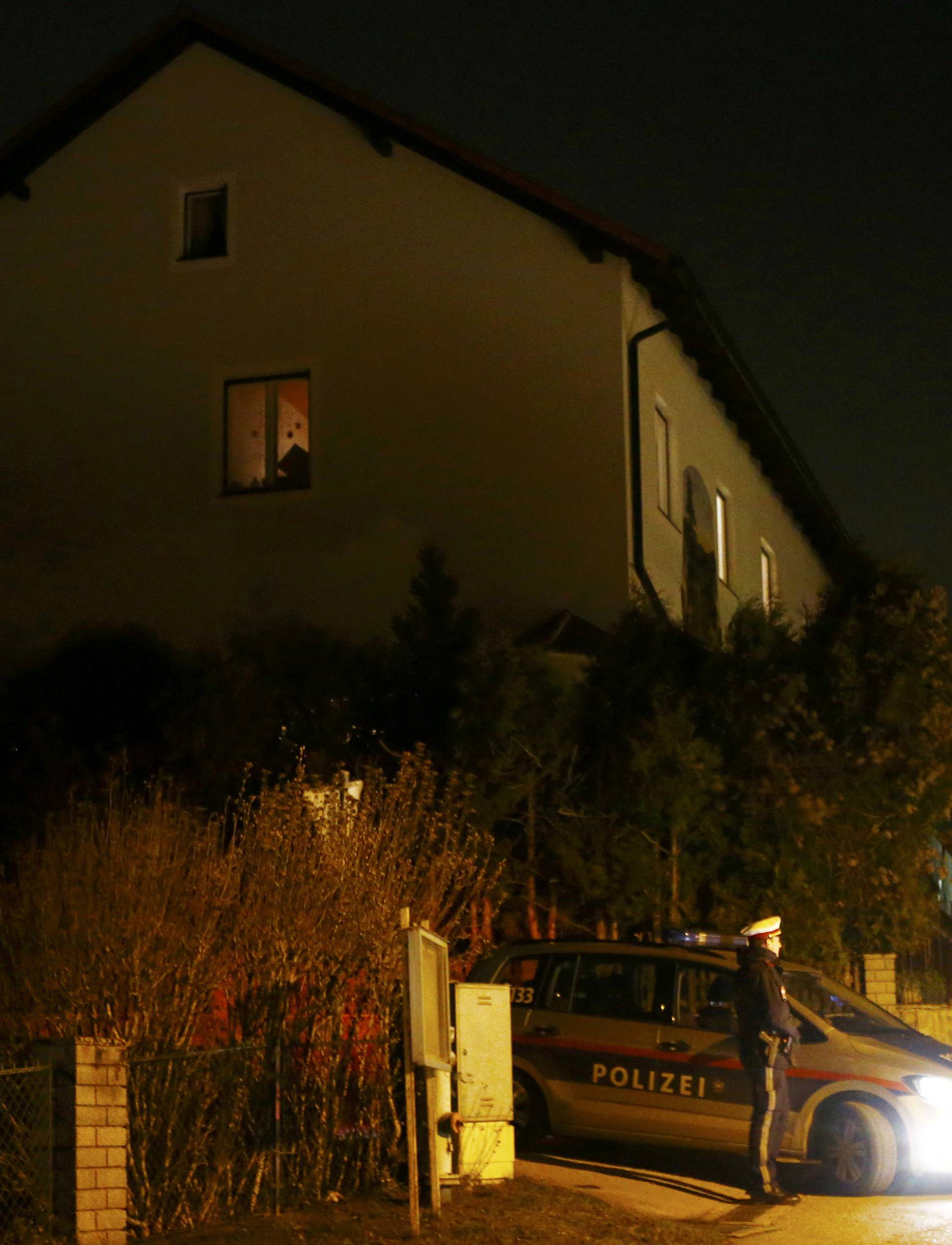 Police stand in front of a house where six people were found dead in Boeheimkirchen