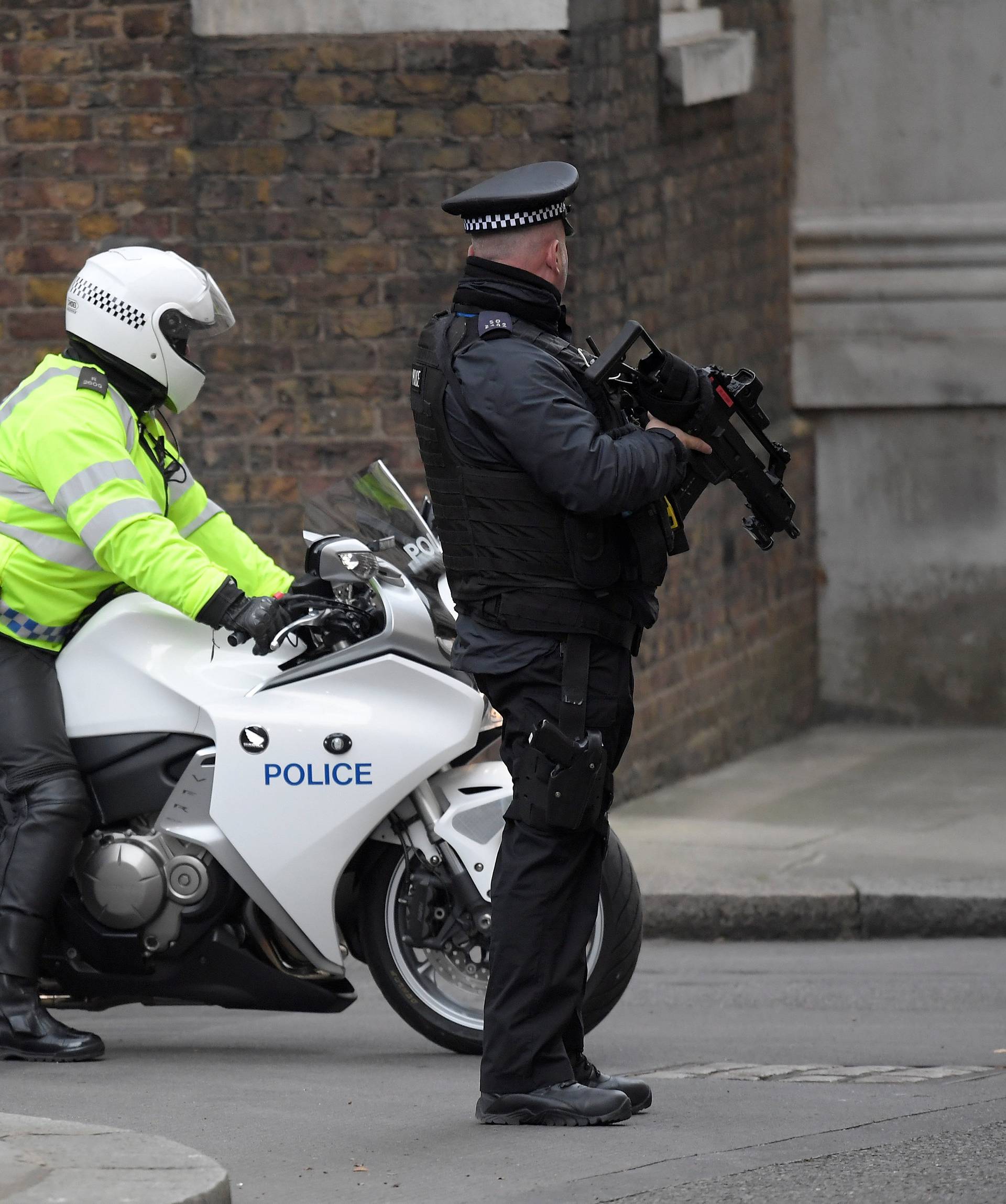 An armed police officer and police motorcycle outrider stand on duty in Downing Street, London