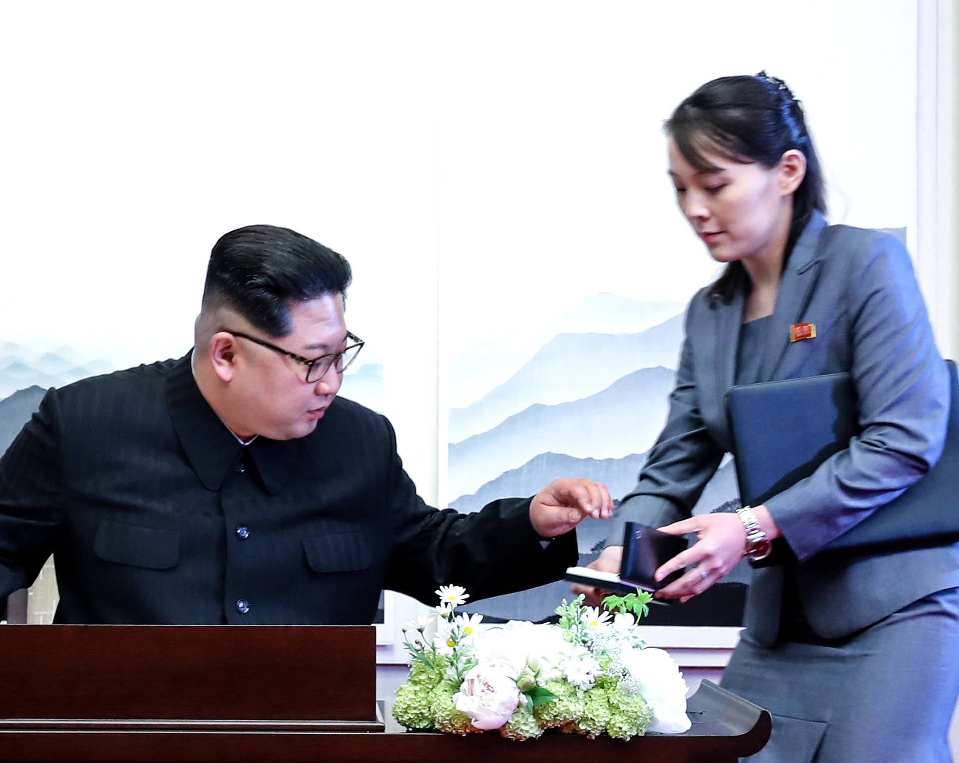 North Korean leader Kim Jong Un prepares to write in a guestbook with his sister Kim Yo Jong during their meeting at the Peace House