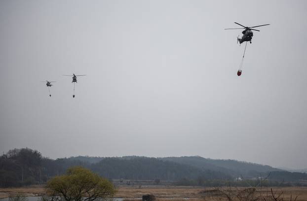 South Korean Army's Surion helicopters fly during an operation as a wildfire burns, in Uiseong