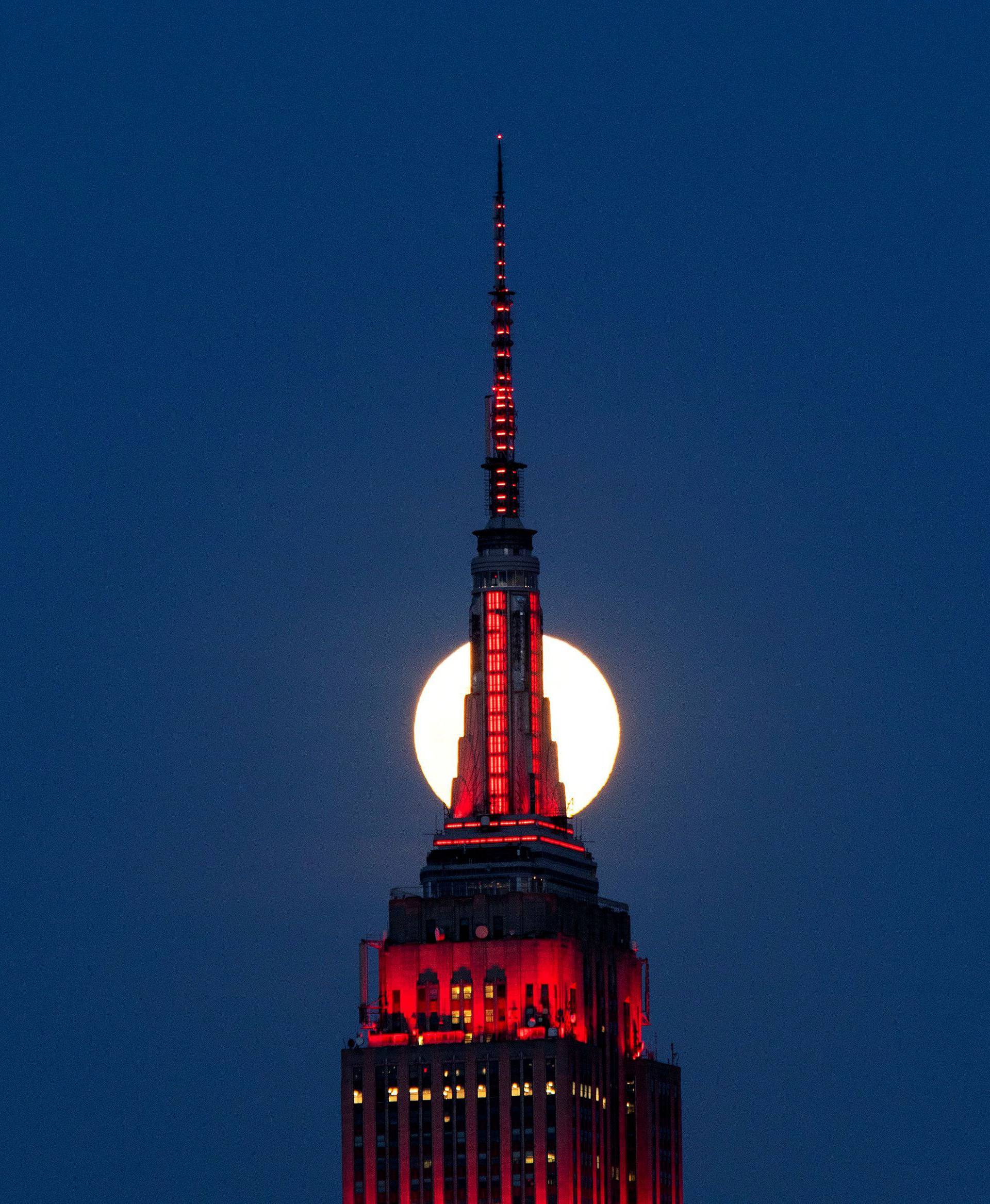 The Supermoon rises behind the Empire State Building while it glows red in solidarity with those infected with coronavirus as the outbreak of the disease (COVID-19) continues in the Manhattan borough of New York City, as it is seen from Hoboken
