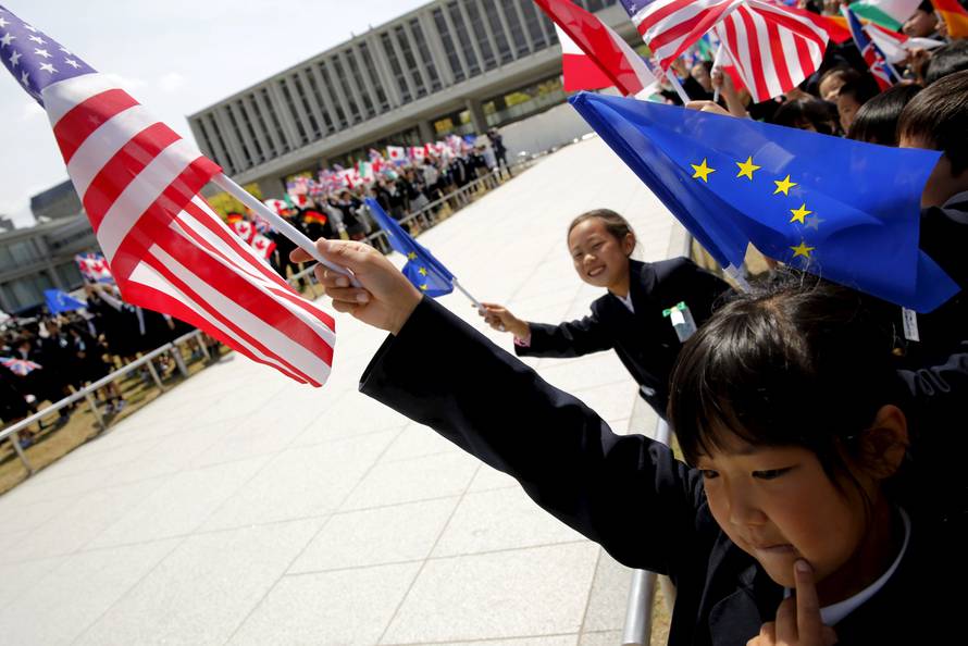 Children hold flags from G7 countries, including a little girl with a U.S. flag, in the wind as the foreign ministers visit Hiroshima Peace Memorial Park and Museum in Hiroshima, Japan