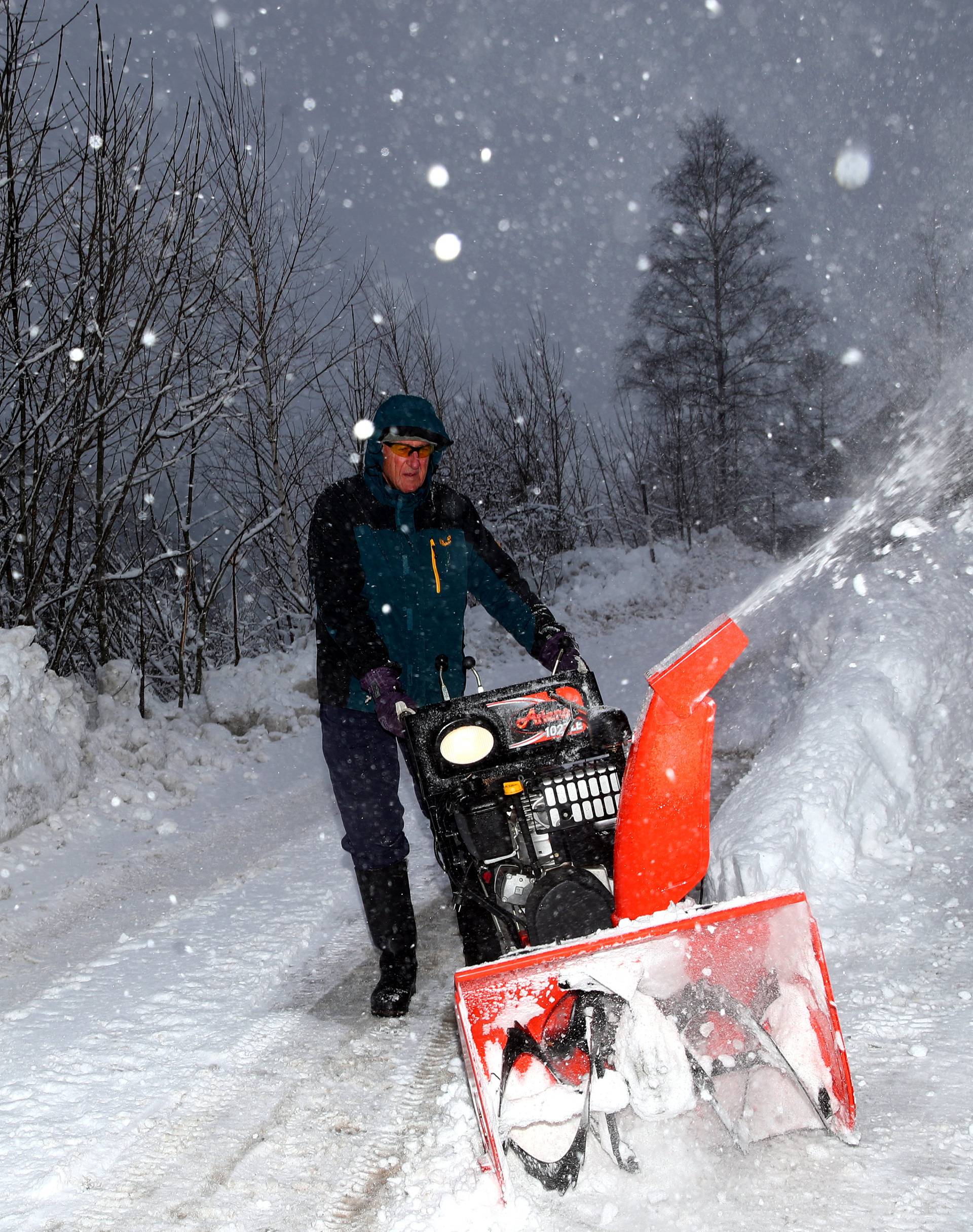 A man removes snow from a road during heavy snowfall in Eisenerz