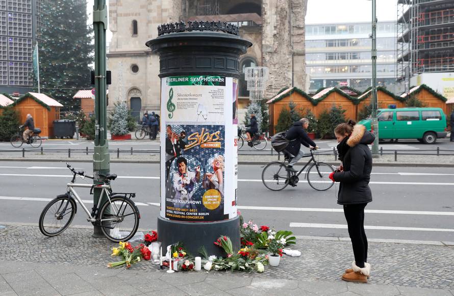 A woman prays near the area where a truck which ploughed into a crowded Christmas market in the German capital last night in Berlin