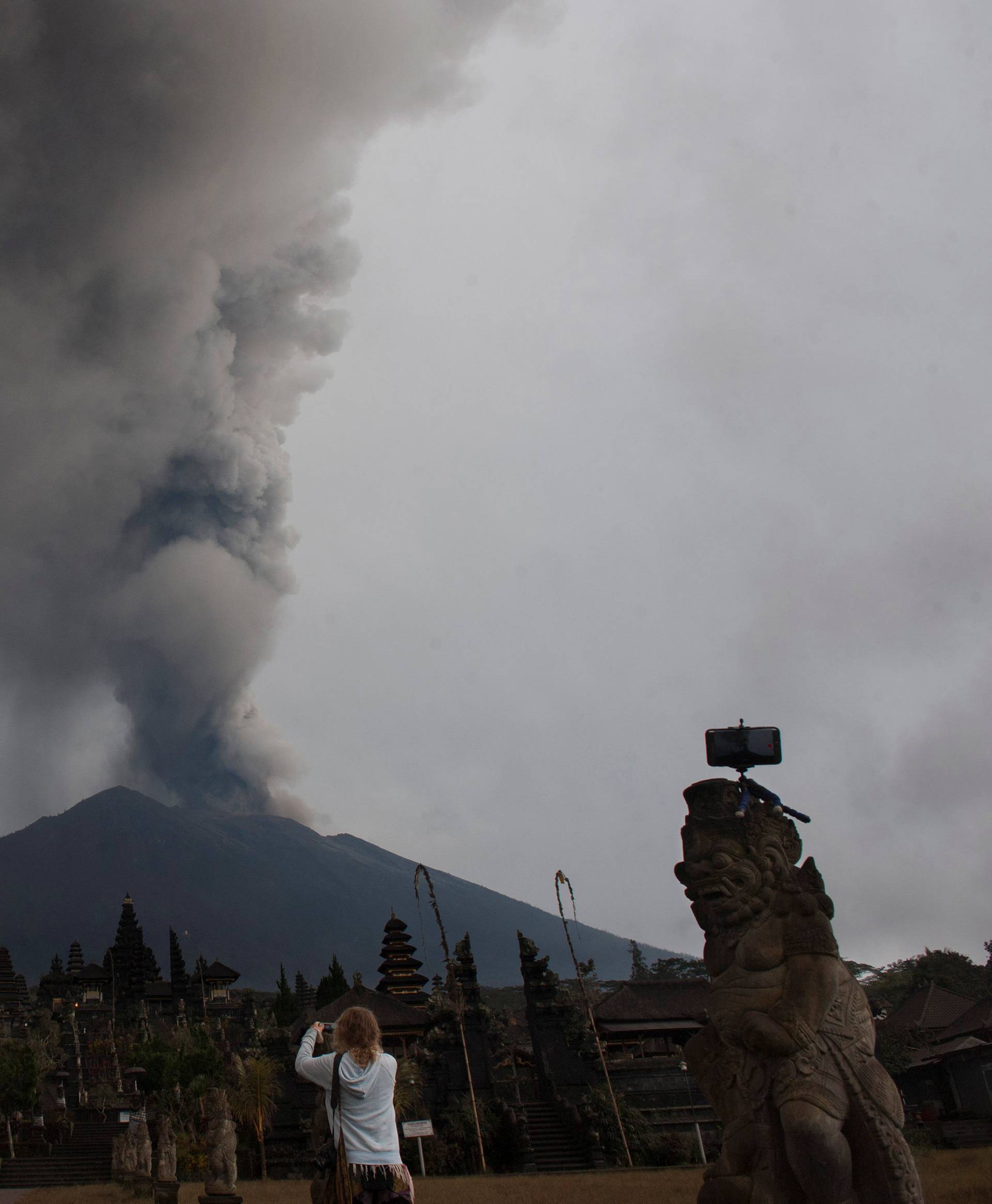 A tourist takes a picture of Mount Agung eruption at Besakih temple in Karangasem