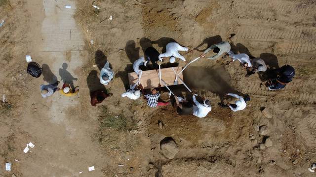 People bury a body of a victim who died due to the coronavirus disease (COVID-19), at a graveyard in New Delhi