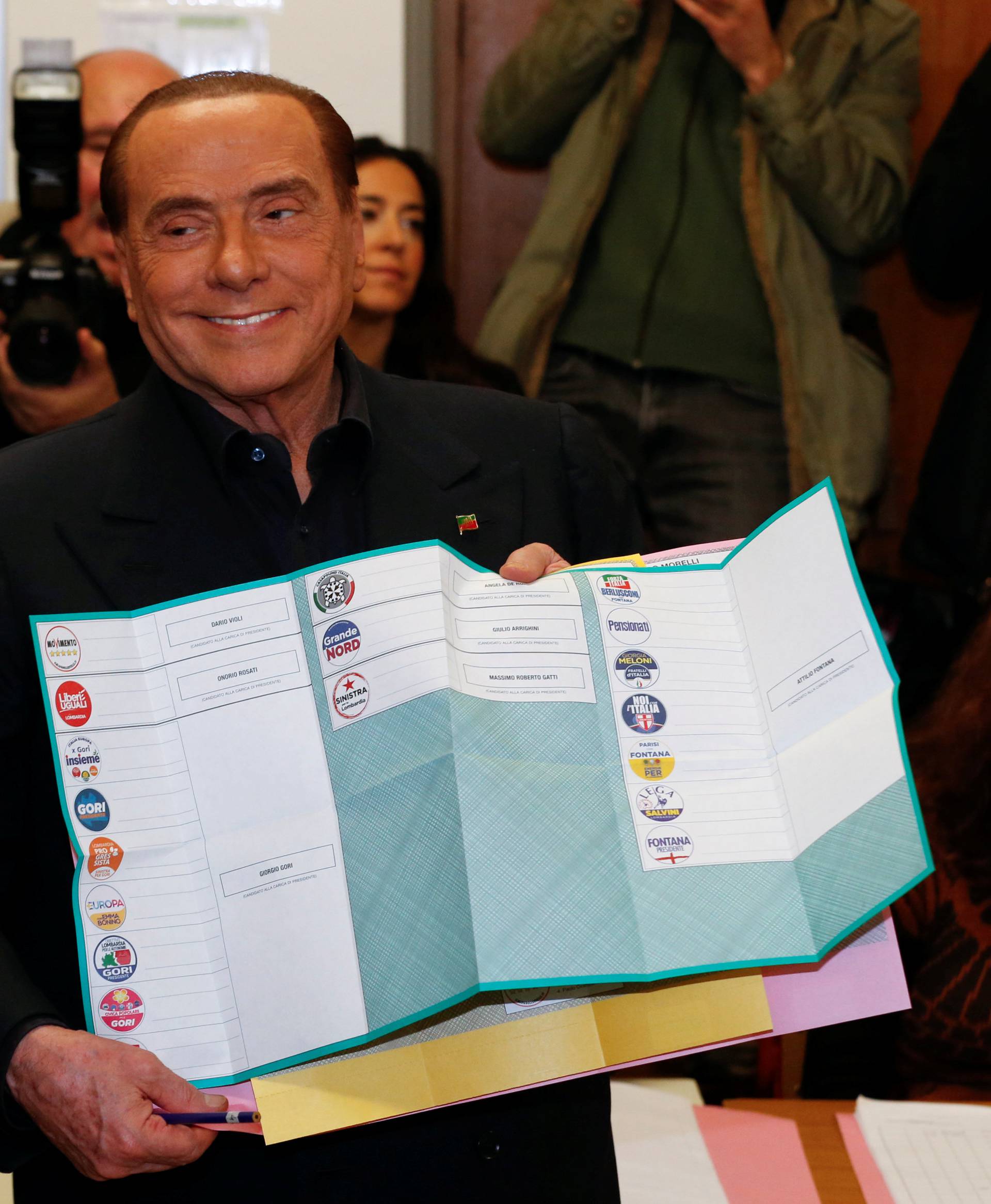 Forza Italia party leader Silvio Berlusconi holds his ballot as he prepares to cast his vote at a polling station in in Milan