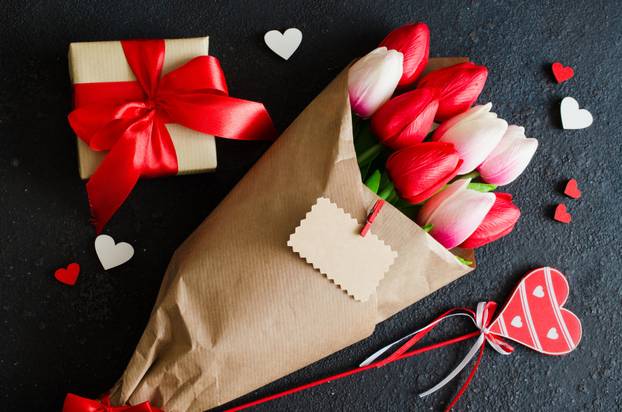 Bouquet of tulips and gift box on dark background.