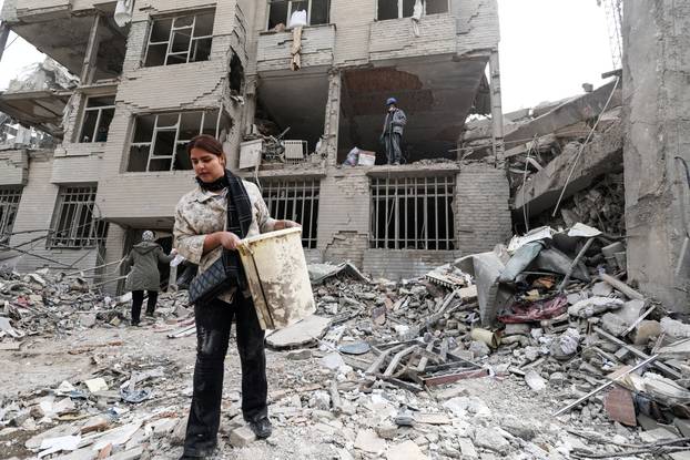A woman gathers the remaining furniture from an apartment damaged by an airstrike, in Tehran