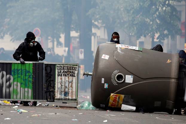 Masked protesters take cover during clashes with French riot police at the May Day labour union rally in Paris