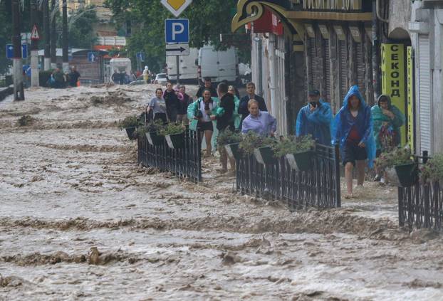 People walk along a flooded street following heavy rainfall in Yalta