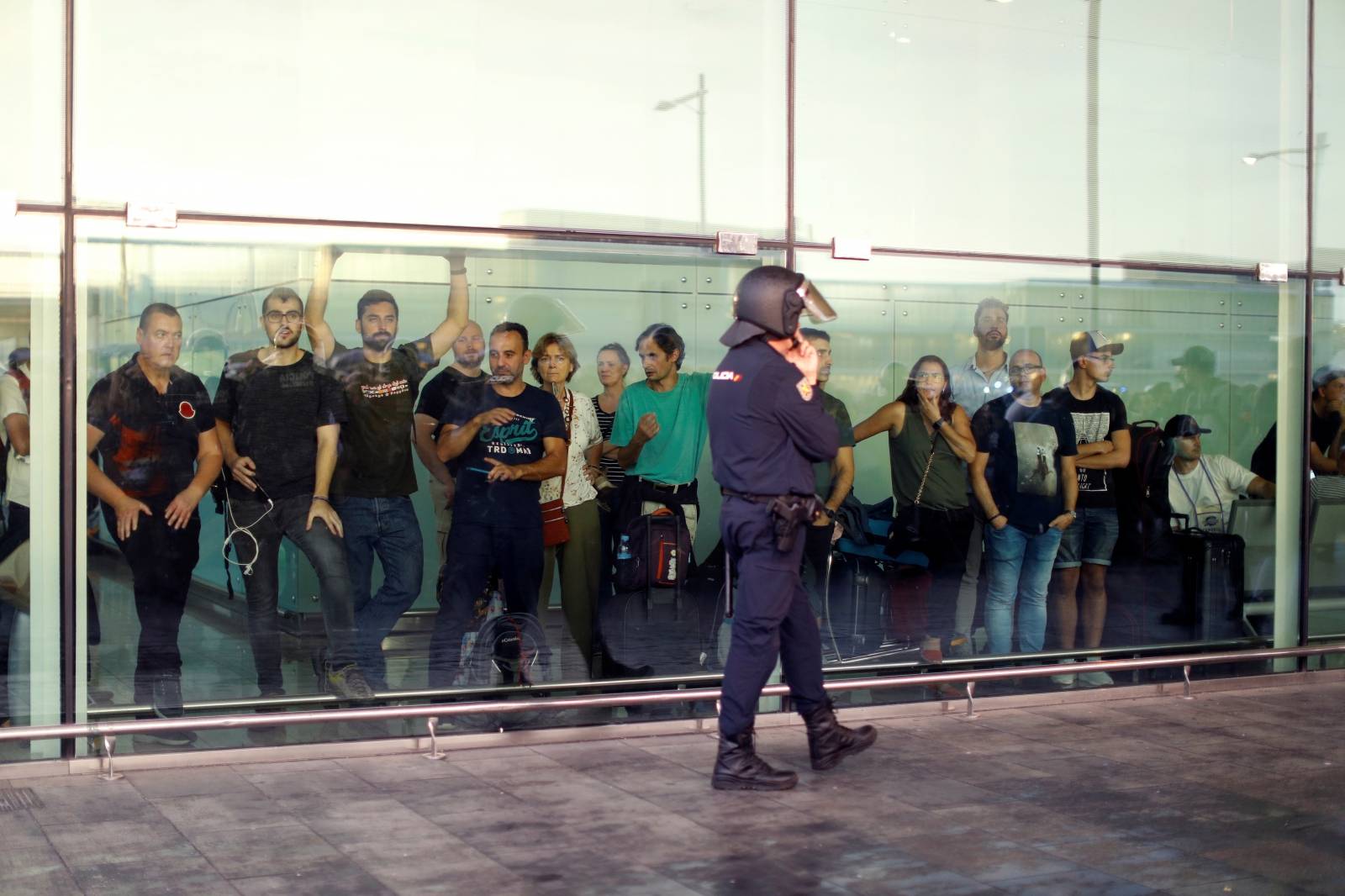 Passengers look as a police officer walks past at Barcelona's airport, during a protest after a verdict in a trial over a banned independence referendum