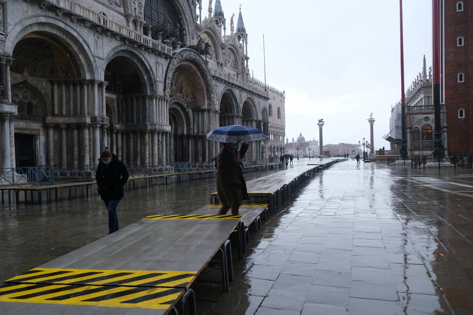 People walk in St. Mark's Square during high tide as the flood barriers known as Mose are raised for the second time, successfully protecting the lagoon city from flooding, in Venice