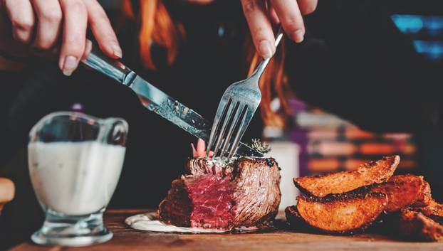 Woman,Hands,With,Fork,And,Knife,Eating,Beef,Steak,In