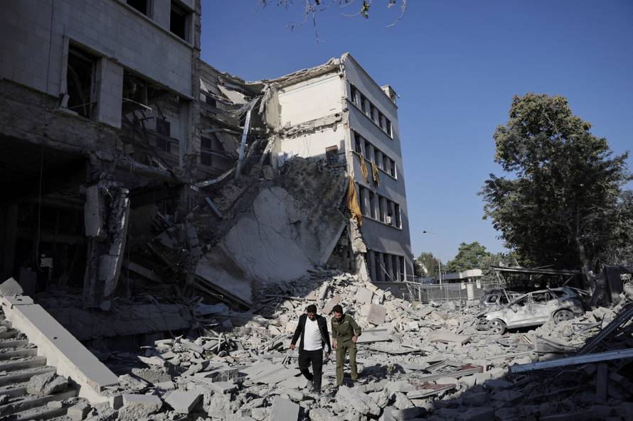 People gather near a damaged site, in Damascus