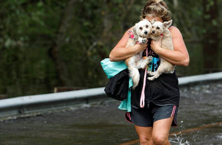 Lisa Shackleford hugs her pet dogs Izzy (L) and Bella as she wades through flood waters to safety while the Northeast Cape Fear River breaks its banks in the aftermath Hurricane Florence in Burgaw, North Carolina