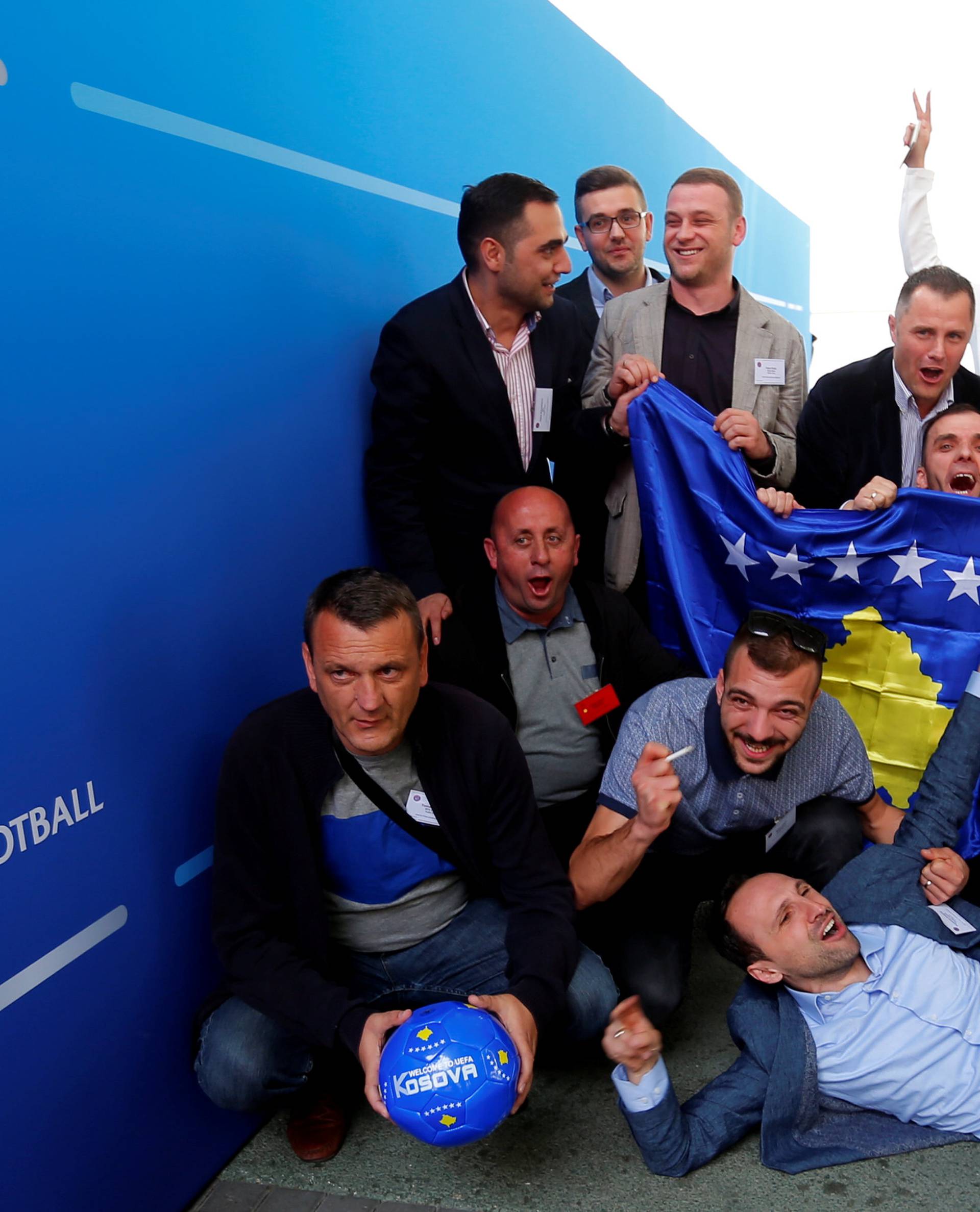 Members of the Kosovo media team celebrate outside the convention centre where the European football group UEFA admitted Kosovo as its newest member in Budapest