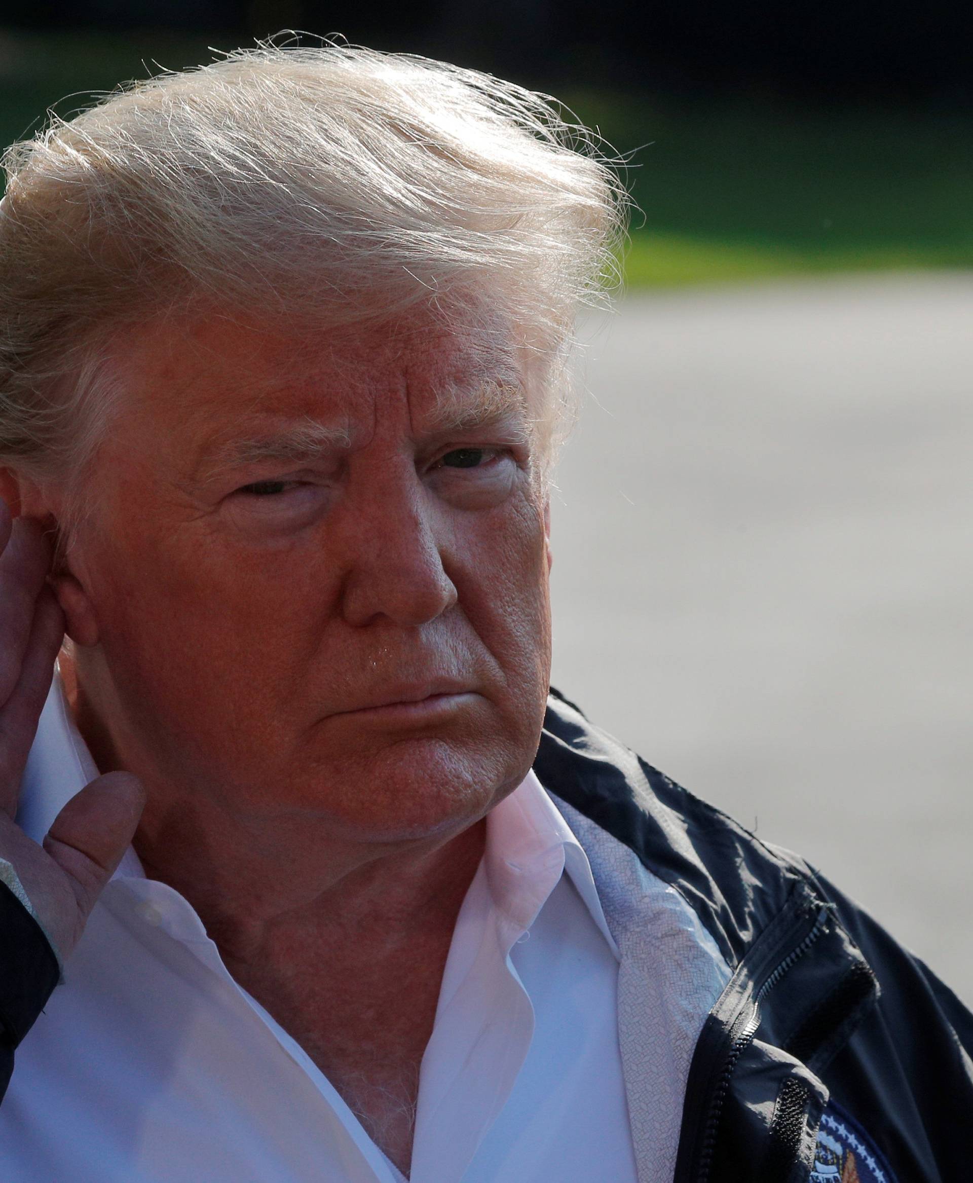 U.S. President Donald Trump listens to a question from a reporter before departing the White House in Washington