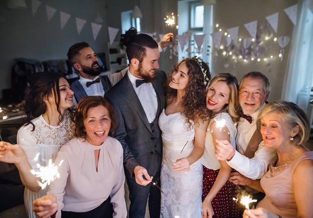 A young bride, groom and guests posing for a photograph on a wedding reception.