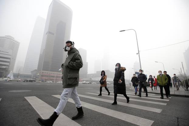 A man wearing a respiratory protection mask walks toward an office building during smog in Beijing