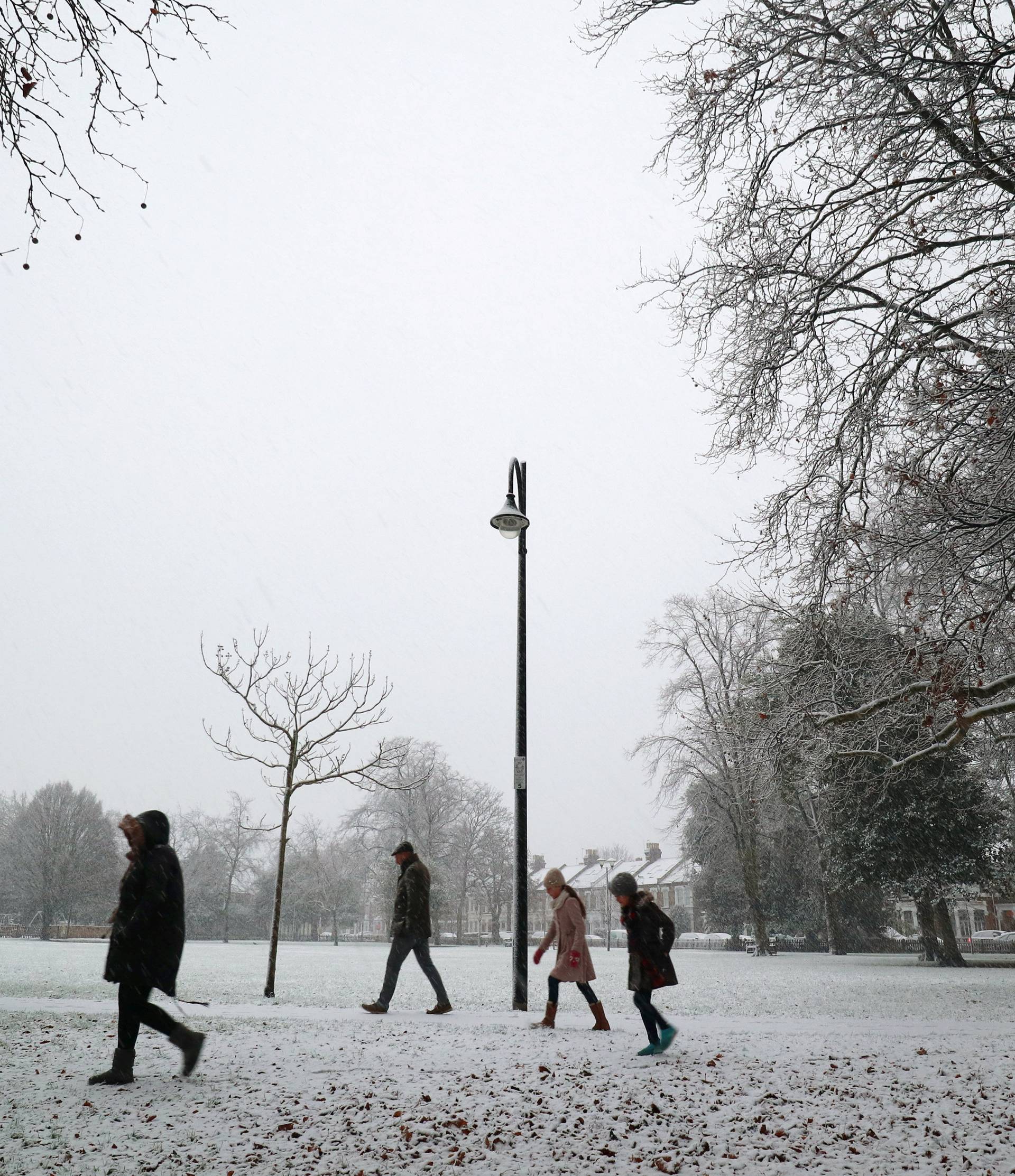 People walk in the first snow to settle in the year in Wanstead, in London