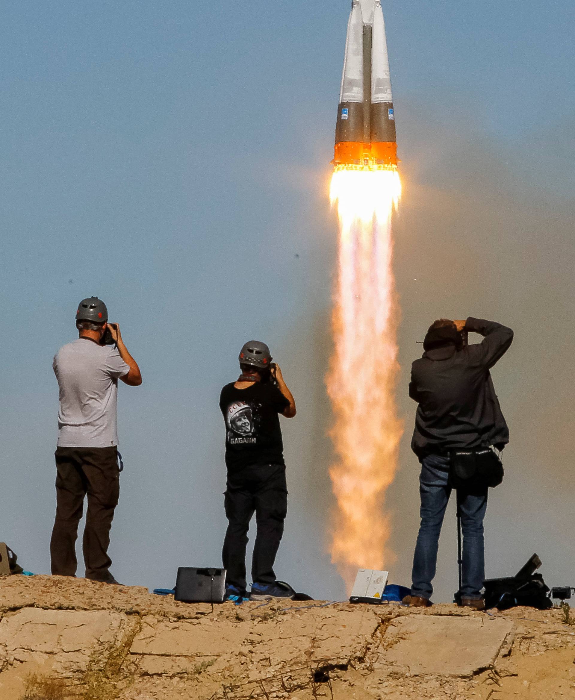 Photographers take pictures as the Soyuz MS-10 spacecraft carrying the crew of astronaut Nick Hague of the U.S. and cosmonaut Alexey Ovchinin of Russia blasts off to the International Space Station (ISS) from the launchpad at the Baikonur Cosmodrome