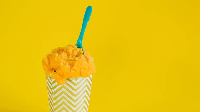 yellow fruit ice cream or frozen yogurt in stripped  a cup with 