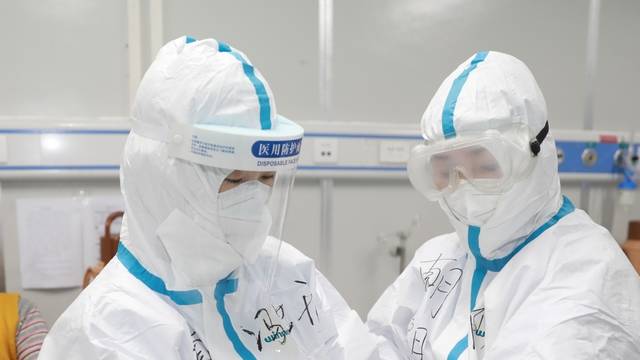 Medical worker writes down a patient's dietary information on a colleague's protective suit inside Leishenshan hospital in Wuhan