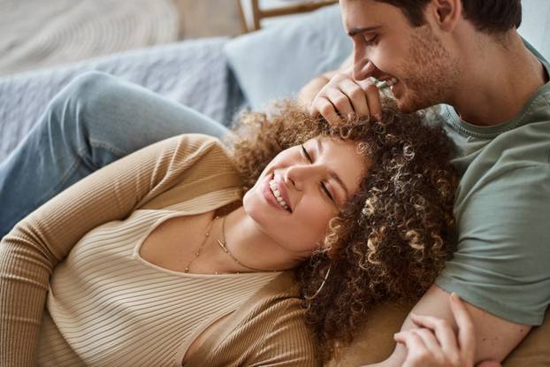 Happy loving couple hug with love and tenderness in indoor bedroom leisure activity