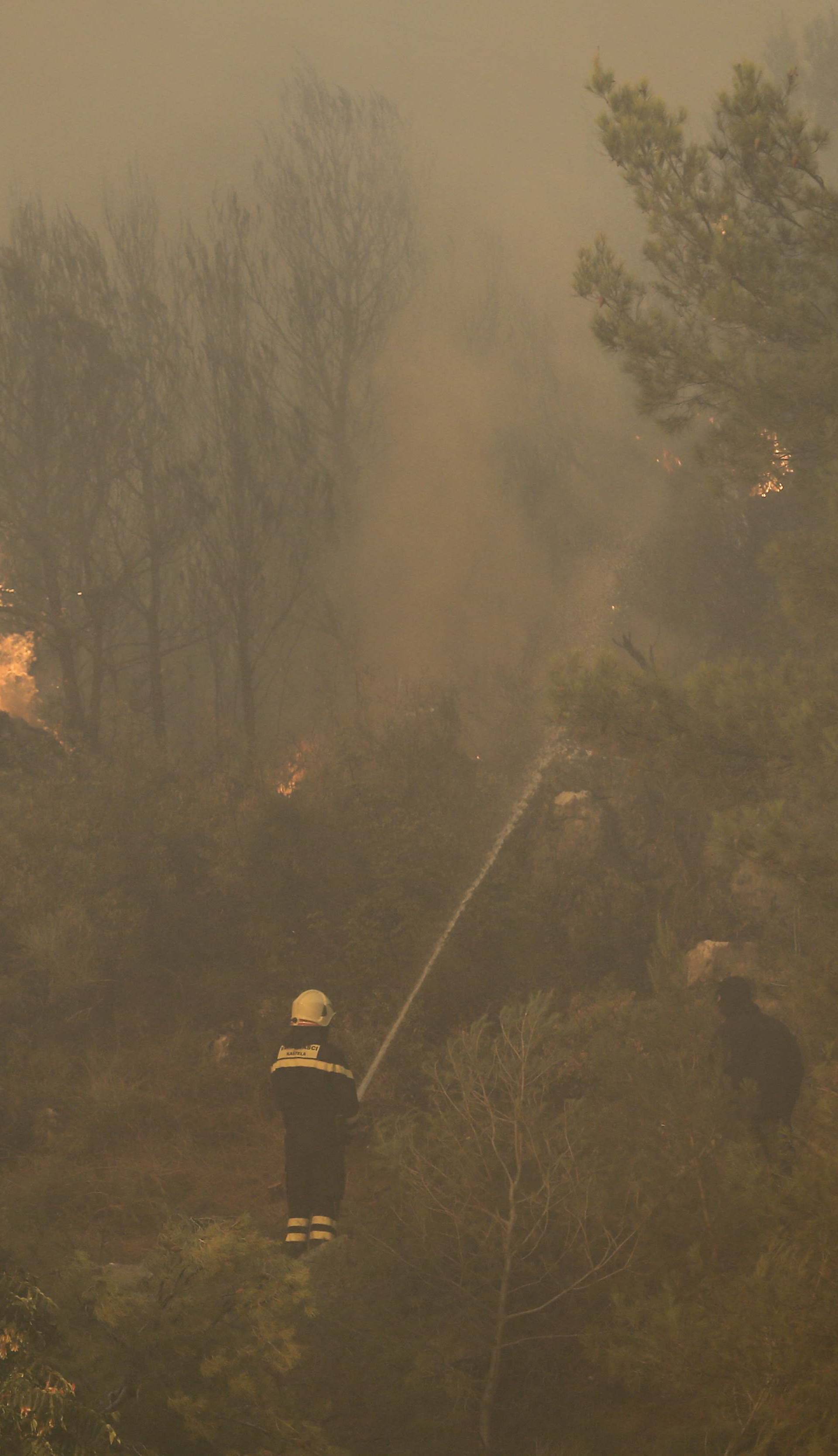 Firefighters try to extinguish a wildfire in the village of Mravince near Split