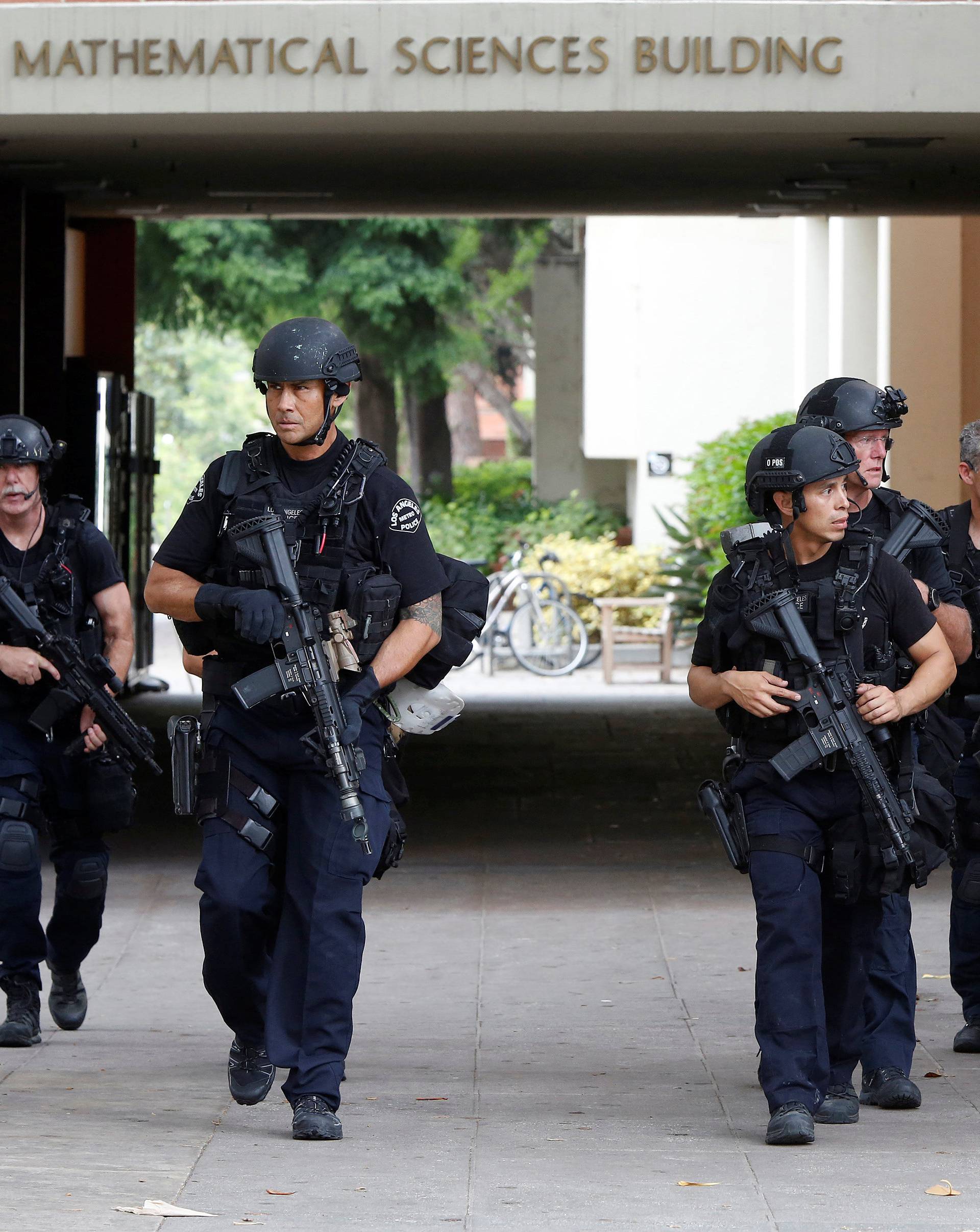 Police officers conduct a search at the UCLA campus after it was placed on lockdown following reports of a shooter that left 2 people dead in Los Angeles, California