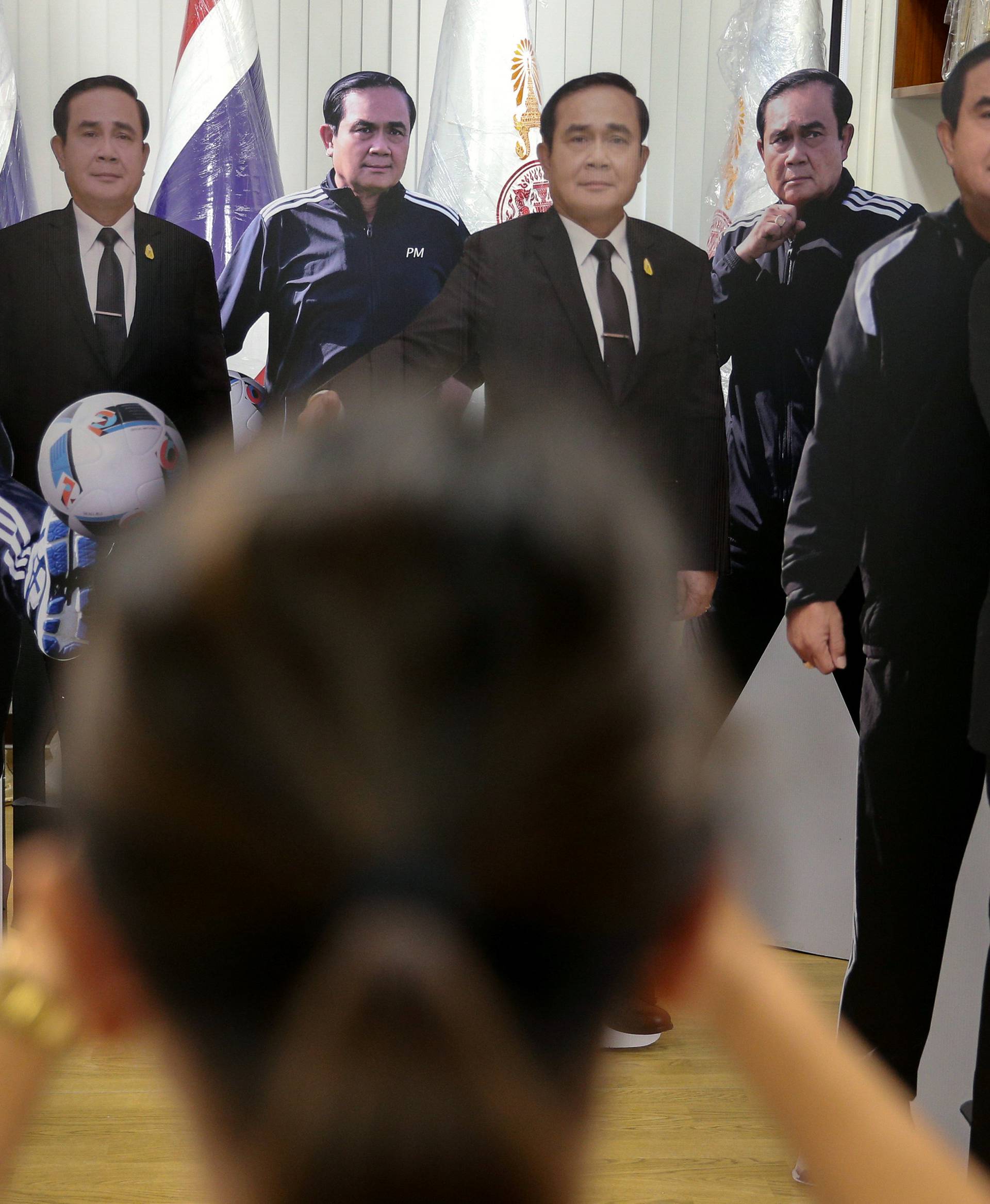 A journalist takes a photo of cardboard cut-outs of Thailand's Prime Minister Prayuth Chan-ocha at Government House in Bangkok