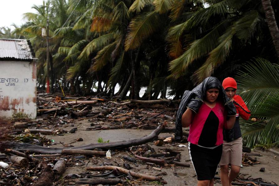 Locals walk along a street near debris as Hurricane Irma moves off the northern coast of the Dominican Republic, in Nagua