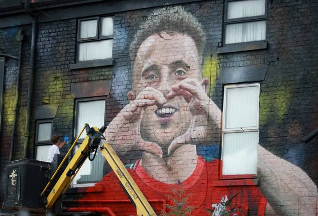 Artist John Culshaw works on a mural of late Liverpool player Diogo Jota on the side of a pub in Liverpool