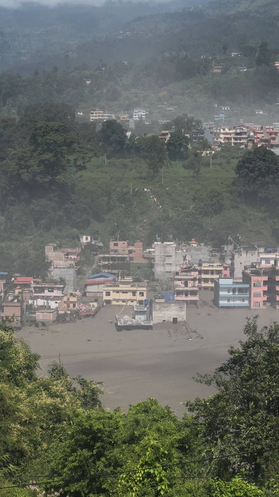 Partially submerged buildings along the riverbank due to a flash flood in Nuwakot district