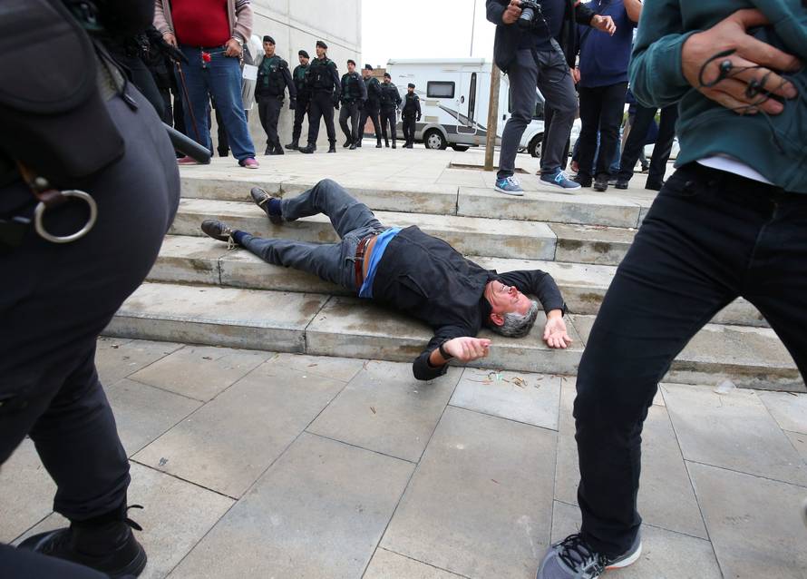 A man falls to the ground during scuffles with Spanish Civil Guard officers outside a polling station for the banned independence referendum in Sant Julia de Ramis